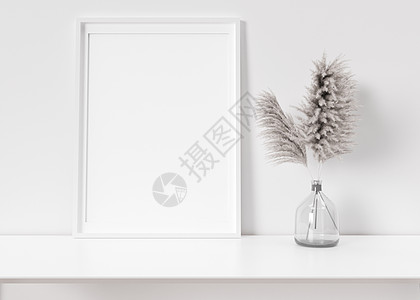 白色相框站在白色架子上的空垂直相框 框架模拟 复制图片 海报的空间 您的作品的模板 特写视图 花瓶中的蒲苇 3D 渲染背景