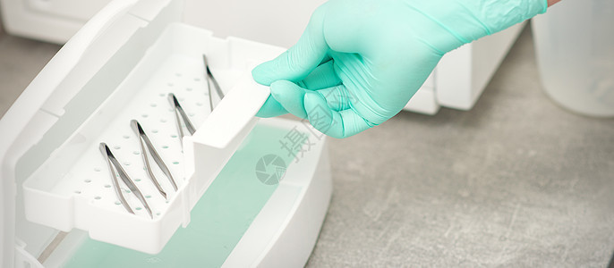 美容师拿着一盘托盘的tweezers 准备用特殊的液体和机器消毒治疗检查职业医生牙科美容院工作修脚诊所卫生图片