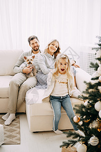 幸福的家庭 妈妈 爸爸和宠物 家庭在明亮的新年内地 有圣诞树动物享受孩子男人父母微笑沙发父亲家居母亲图片