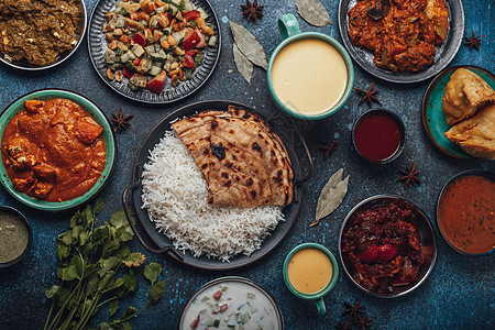 上面生锈的混凝土桌子上将印度民族食品自助餐分散在情调异国草本植物肉汁盘子派对油炸香料餐厅食物图片