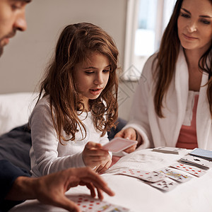 玩她最好的牌 一个年轻家庭在家里一起打牌的游戏背景图片
