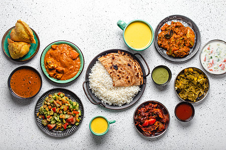 上面白色混凝土桌上的印度族裔食品自助餐食物草本植物肉汁香菜芝士油炸香料盘子乡村送货图片