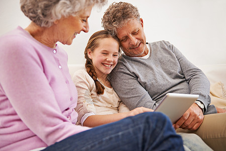 祖父母看着孙女用数码平板电脑看孙女的外公外婆们呢?图片