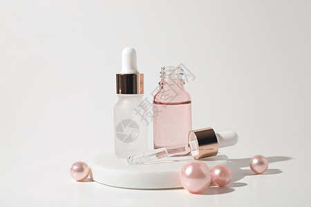 两瓶装有粉红色珍珠的白底玻璃液态透明凝胶 喷水瓶 高压酸 油 血清 皮肤护理产品图片