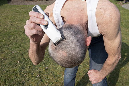 一个灰色头发的中年男子 在花园里用剪刀刮头发外貌发型仪式理发剃须卫生机器短发剃刀理发师图片
