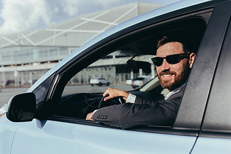 身戴黑色眼镜的商务人士坐在汽车车轮后面微笑成人商业风镜衣服男性男人司机客户运输图片