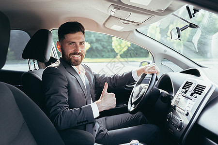 商务人士举起大拇指看镜头 微笑地看着摄影机 想捏紧车内的安全带并使用安全带测试商务男人发动机奢华零售车辆司机正装座位图片