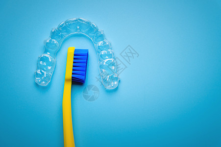 一个黄色的明亮牙刷 上面有塑料新牙套 是蓝色背景 没有人口腔科治疗牙齿卫生矫正保持器括号化妆品牙医刷子图片