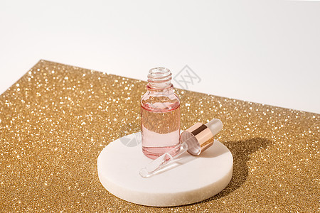 粉红玻璃瓶装整形液态透明凝胶 在白色背景和金皮板上 滴水瓶 高压酸 油 血清 皮肤护理产品 复制空间图片