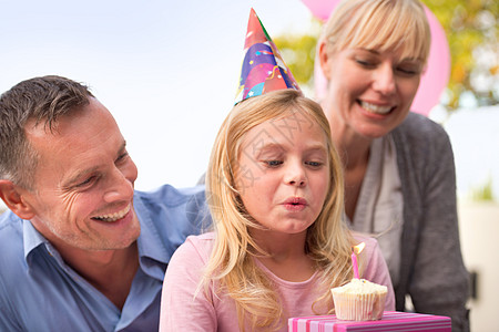 生日女孩的愿望 一个快乐的小女孩和她的父母庆祝她生日的裁剪镜头图片