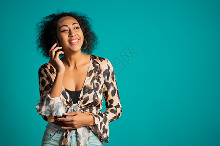 非洲裔美国妇女在电话里说话 从对话者的笑话中微笑 完美的妆容 时尚的装束 复制空间商务女孩快乐照片商业棕色手机技术人士工作室图片