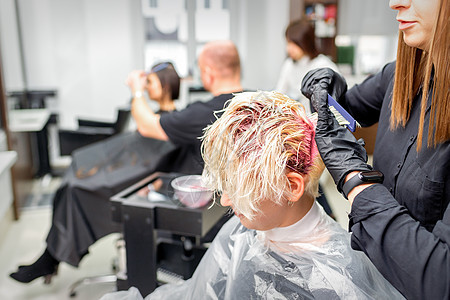 专业理发师用刷子把粉红色染色涂在头发上 毛发彩色概念染料美容师着色剂发型师手套金发客户客厅美发造型师图片