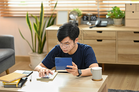 青年男子利用银行贷款和客厅管理开支融资 计算金钱 银行贷款及管理起居室支出图片