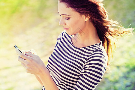 在阳光下社交 一个有吸引力的年轻女性 使用手机户外行动电话图片