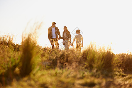 金色的家庭时光 一个年轻家庭在日落时一起散步的全场镜头图片