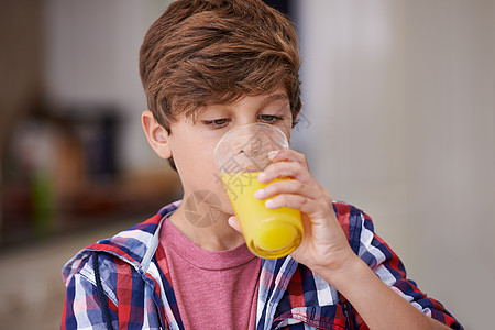 一个小男孩喝了一杯橙汁 喝着果汁 他给自己倒了点果汁孩子们裁剪厨房孩子黑发男生青年橙子享受房子图片