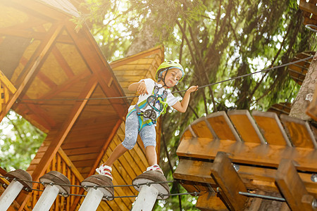 快乐的小女孩在一个绳子公园 在木头背景上行动运动冒险风险闲暇活动学校绳索力量安全图片