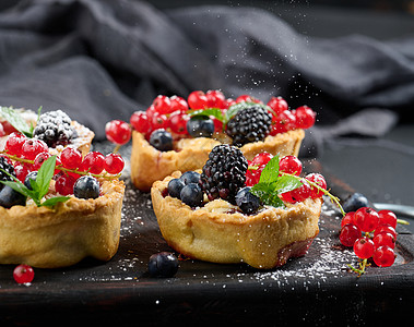 在黑桌上洒满粉末糖的果冻和红花盆传统食物甜点红色脆皮蛋糕棕色糕点水果蛋糕黑色图片