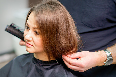 男理发师在美容院为年轻女子做发型  她的头发很像美容院女性造型客厅发型师服务顾客剪发婚礼梳子造型师图片