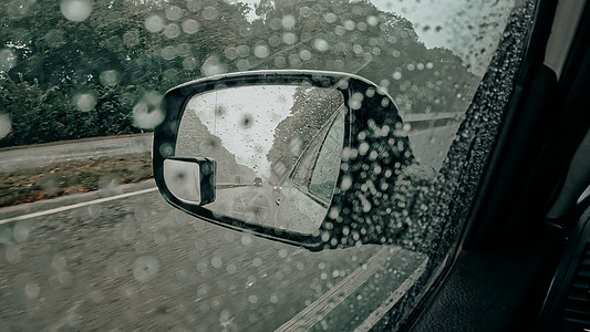 车边司机用雨滴照着车面镜 在雨季 繁忙道路时驾驶汽车图片