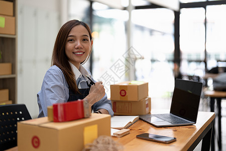 年轻的创业小企业企业家女性在家使用智能手机 在线业务和交付概念营销服务物流包装盒子公司零售商务店铺纸板图片