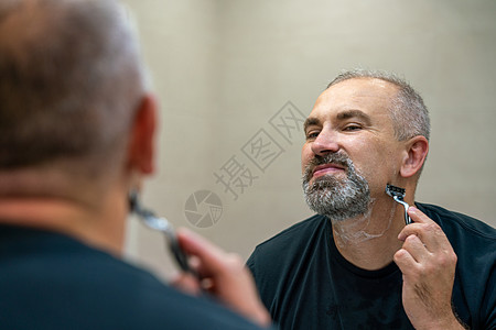 在浴室用剃刀的中年英俊男子凝胶成人胡须镜子男性头发泡沫隔断刮胡子奶油图片
