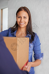 一位美丽的年轻女子在照相机前微笑 她从一个搬运工那里拿了一个箱子 (笑声)图片
