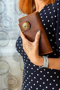 女人手里握着棕色天然皮皮钱包财富手提包手臂金融配饰销售零售魅力奢华购物图片