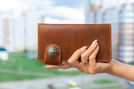 女人手里握着棕色天然皮皮钱包零售手提包奢华优雅货币销售购物离合器女性手臂图片