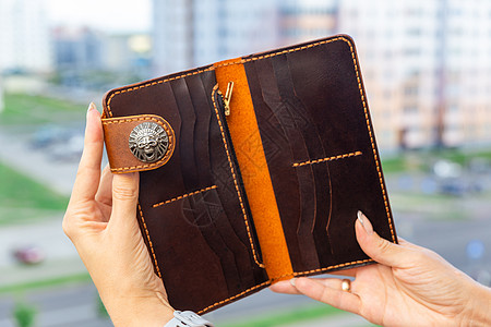 女人手里拿着一个棕色的天然皮夹子魅力零售钱包女性商业手提包离合器金融购物货币图片