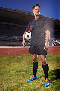 一个年轻的足球运动员站在球场上 拿着一个球 他是个大人物图片