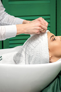在美容院洗发后 理发师用毛巾包着女性头部治疗发型理发美发沙龙护理职业造型师顾客女士图片
