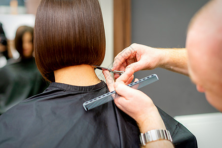 理发师剪了一个黑发女人的头发 发型师正在一家专业美发沙龙为女性客户剪头发 特写理发治疗工作室尖端梳子修剪发型剪刀爆头工作图片