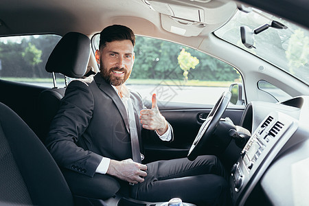 商务人士举起大拇指看镜头 微笑地看着摄影机 想捏紧车内的安全带并使用安全带商业男人驾驶企业家发动机奢华座位运输成功领导图片