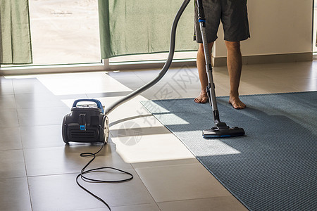 拍到一个男人在地毯上吸尘 一是房间窗户躯干打扫家庭阳光房子男性家电命令家务图片