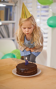 吹出她的生日蜡烛 一个年轻女孩在生日蛋糕上点燃了蜡烛图片