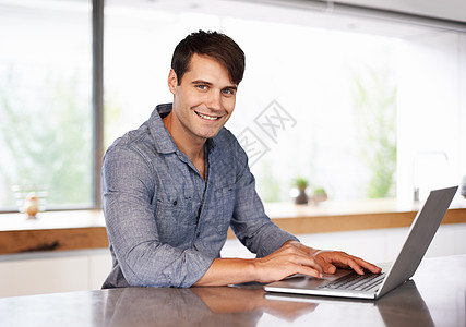 他的世界触手可及 一个年轻男子在使用笔记本电脑时对着镜头微笑的画像图片
