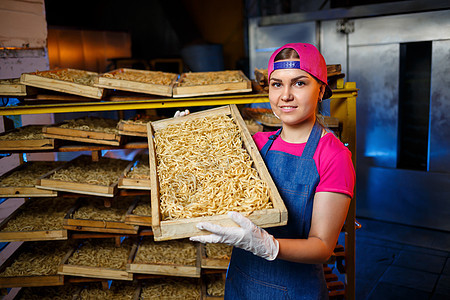 做面条 面食厂 意大利面生产 生意大利面 拿着一盒意大利面的工人 女孩在意大利面的生产中工作工业农产品生食劳动商品金融产品食物工图片