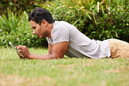 有线后院 一个英俊的年轻人 躺在草地上 用数字平板电脑药片技术闲暇裁剪成人男人屏幕记事本互联网绿色图片