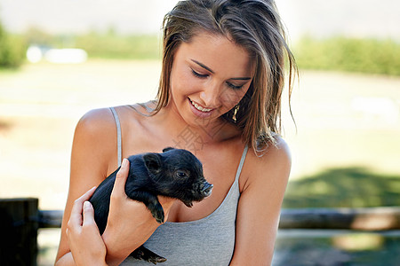 认识农场上的最新成员 一个年轻女人拿着可爱的小猪仔 她很可爱女性阳光微笑太阳皮肤青年小猪晴天乐趣成人图片
