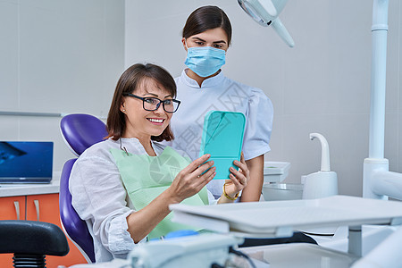 女病人与牙医 坐在牙科椅子上看镜子的病人一起看牙医口腔科医院女性工作医生办公室卫生中年保健反射图片