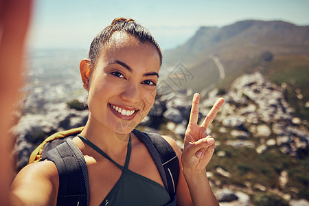 夏季 在山上徒步自拍 快乐的女人和在大自然中健身 进行锻炼 旅行和徒步探险 面孔 微笑和和平标志着女游客背着背包在户外探索图片