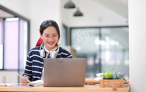 亚洲女学生在线学习班学习在线视频通话 zoom 老师 快乐的亚洲女孩用电脑笔记本电脑在线学习英语女士桌子耳机教育办公室学校青少年图片