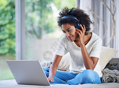 一位年轻女性在家使用笔记本电脑时戴耳机 这名年轻女性则穿着耳机图片