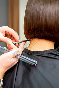 理发师剪了一个黑发女人的头发 发型师正在一家专业美发沙龙为女性客户剪头发 特写顾客工作室理发店美容青少年店铺造型师护理发型尖端图片