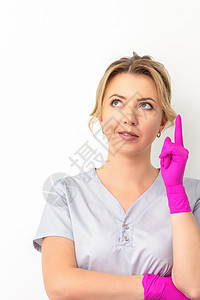 年轻天主教女医生身着橡皮手套 穿着一指头举起的医疗制服 在白色背景和复制空间上抬头看 其肖像黑发外套快乐护士女性成人工作室美容师图片