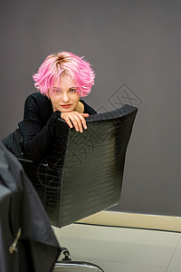 一位美丽的黑人年轻女子的肖像 穿着新的短粉红色发型 在理发厅坐着椅子上做美容师理发师调子光泽度染色染料护理造型治疗沙龙理发图片