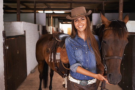 女孩最好的朋友 一个年轻女人在照顾她的马匹动物牛仔闲暇帽子成人休闲服女性喜悦关爱微笑图片