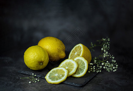 寒冬中 光亮的黄柠檬和吉卜赛人的鲜花在黑暗背景的桌子上 紧靠在他们旁边图片