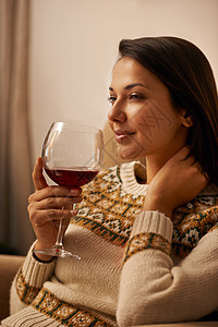 享用一杯美酒 一个迷人的年轻女人在家里放松时享用一杯葡萄酒图片